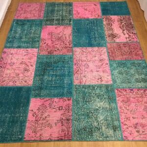 May include: A patchwork rug with a teal and pink color scheme. The rug is made of different pieces of fabric sewn together to create a unique design.