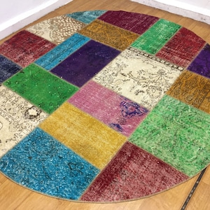 May include: A round patchwork rug with a variety of colors and patterns, including red, green, blue, yellow, and purple.