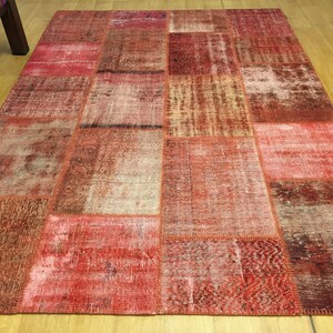 May include: A red patchwork rug with a variety of patterns and textures. The rug is made from recycled materials and has a distressed look.