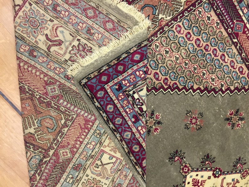 May include: Close-up of a multi-colored rug with intricate patterns. The rug is made of wool and has a fringe border. The rug is folded in half, revealing a different pattern on the underside.