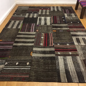 May include: A patchwork rug with a variety of colors and patterns, including brown, gray, red, and white. The rug is made of wool and has a hand-woven texture.