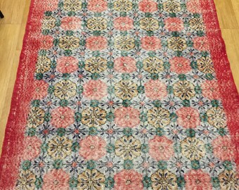 Könnte beinhalten: Ein Vintage-Teppich mit einem geometrischen Muster in Rosa-, Grün- und Weißtönen. Der Teppich hat einen roten Rand.