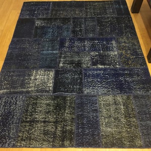 Puede incluir: Una alfombra azul de patchwork con una variedad de texturas y patrones. La alfombra está hecha de denim reciclado y tiene un aspecto desgastado.