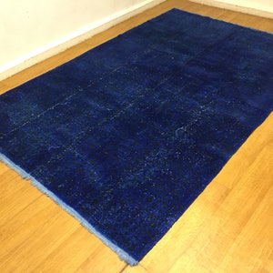May include: A deep blue rug with a subtle pattern, laid out on a wooden floor.