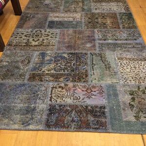 Könnte beinhalten: Ein Patchwork-Teppich aus verschiedenen Stoffstücken in Blautönen, Braun und Weiß. Der Teppich hat einen Used-Look und besteht aus verschiedenen Mustern und Designs.
