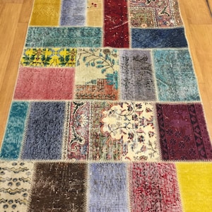 May include: A colorful patchwork rug with a variety of patterns and colors, including red, blue, yellow, and green. The rug is made of different pieces of fabric that have been sewn together.