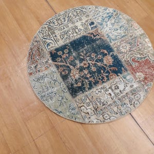 May include: A round, multi-colored patchwork rug with a floral design in the center. The rug is made of different fabrics and has a vintage look.