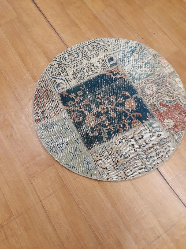 May include: A round, multi-colored patchwork rug with a floral design in the center. The rug is made of different fabrics and has a vintage look.