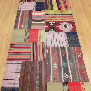 Puede incluir: Una alfombra de patchwork colorida con una variedad de patrones geométricos y rayas en tonos de rojo, verde, azul y marrón.