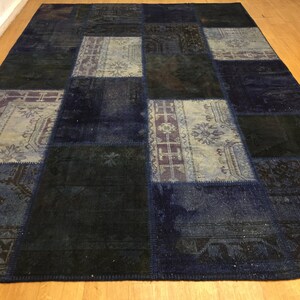 Könnte beinhalten: Ein Patchwork-Teppich in Blau- und Schwarztönen. Der Teppich besteht aus verschiedenen Stoffstücken, die zusammengenäht wurden und ein einzigartiges und interessantes Design ergeben.