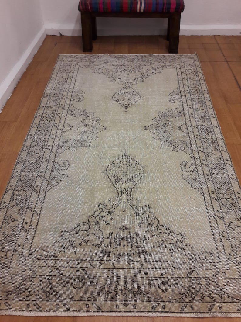 May include: A vintage rug with a light beige background and a dark brown floral pattern. The rug has a distressed look and is perfect for adding a touch of rustic charm to any room.