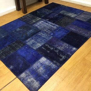 May include: A blue patchwork rug with a distressed look. The rug is made of different shades of blue fabric and has a unique, handmade appearance.