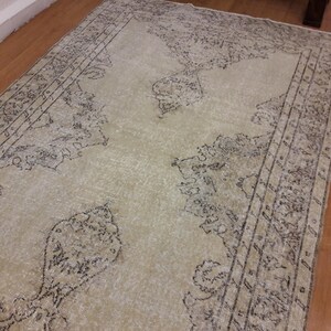 May include: A vintage-style rug with a cream background and a black floral pattern. The rug has a distressed look and is made of a soft, woven material.