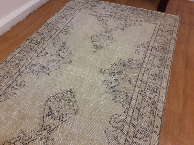 May include: A vintage-style rug with a cream background and a black floral pattern. The rug has a distressed look and is made of a soft, woven material.