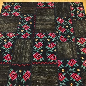 Peut inclure: Un tapis patchwork avec un fond noir et un motif floral dans les tons rose, rouge et vert.