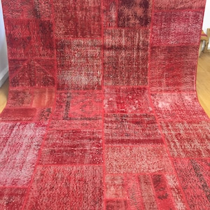 May include: A red patchwork rug with a distressed look. The rug is made of different pieces of fabric sewn together, creating a unique and interesting pattern.