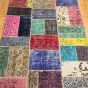 May include: A colorful patchwork rug with a variety of patterns and colors, including red, blue, green, yellow, and pink. The rug is made of different pieces of fabric sewn together.