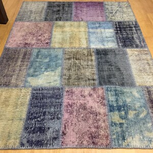 Könnte beinhalten: Ein Patchwork-Teppich mit einer Vielzahl von Farben und Texturen, darunter Blau, Lila, Braun und Beige. Der Teppich besteht aus vielen verschiedenen Stoffquadraten, die zusammengenäht wurden.