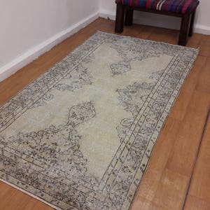 May include: A light beige rug with a dark gray patterned design. The rug has a distressed look and a faded appearance.