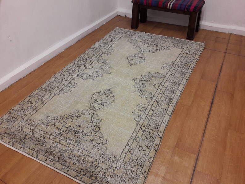 May include: A light beige rug with a dark gray patterned design. The rug has a distressed look and a faded appearance.