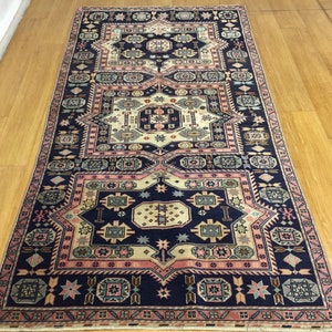 May include: A traditional Persian rug with a navy blue background and intricate geometric patterns in shades of pink, cream, and green.