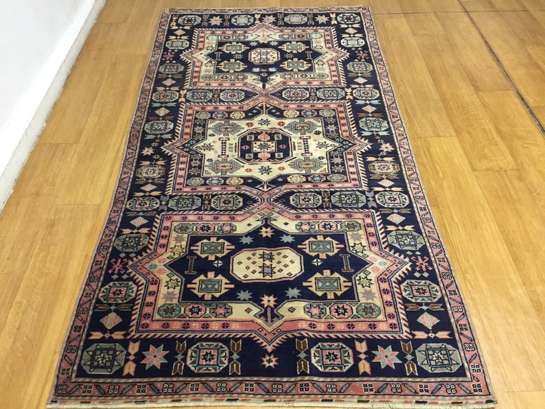 May include: A traditional Persian rug with a navy blue background and intricate geometric patterns in shades of pink, cream, and green.