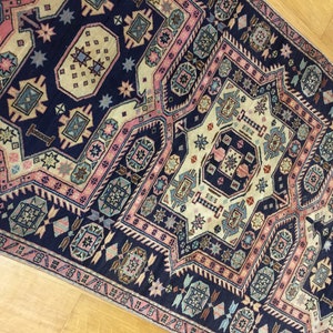 May include: A vintage rug with a navy blue background and intricate geometric patterns in shades of pink, beige, and blue.