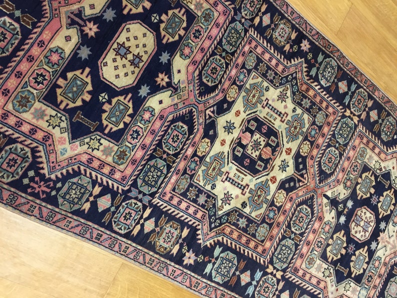 May include: A vintage rug with a navy blue background and intricate geometric patterns in shades of pink, beige, and blue.