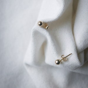 May include: A pair of gold ball stud earrings. The earrings are small and simple, and they are perfect for everyday wear.