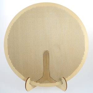 May include: A round wooden embroidery hoop with a stand. The hoop is made of natural wood and has a grid pattern.