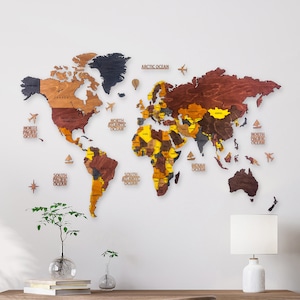 A wooden world map with a brown, yellow, and black color scheme. The map is divided into continents and countries, with each country labeled with its name. The map is mounted on a white wall.