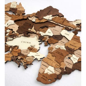 Close-up of 3D wooden world map showing Asia and Africa with engraved country names in mixed brown tones