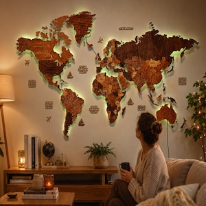 May include: A large, multi-layered wooden world map wall art piece featuring varying brown wood tones and integrated backlighting that casts a soft glow. The map includes cut-out continents, islands, and small decorative wooden icons of planes and ships.