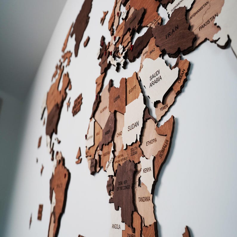 Close-up of 3D wooden world map showing Africa with engraved country names in mixed brown tones on a white wal