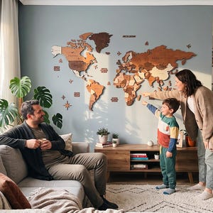 May include: A large, multi-layered wooden world map wall art installation featuring various shades of brown and tan wood. The map includes laser-cut continents, islands, and ocean labels, mounted directly onto a solid light blue wall surface.