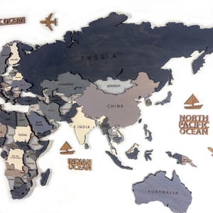 Detail shot of dark grey 3D wooden world map — laser-engraved Russia, China, India and Australia in layered grey and white birch plywood