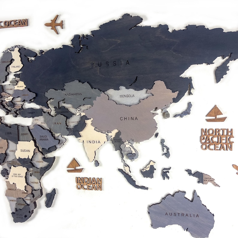 Detail shot of dark grey 3D wooden world map — laser-engraved Russia, China, India and Australia in layered grey and white birch plywood