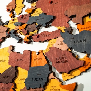 Detail shot of colorful 3D wooden world map — vibrant yellow, orange, grey and brown wood tones across Europe, Middle East and North Africa
