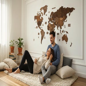3D wooden world map as anniversary gift for couples — large dark brown wall art displayed in a cozy boho living room with couple sitting below