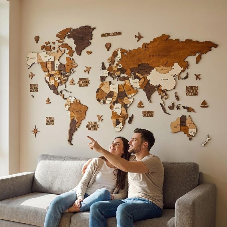 3D wooden world map above sofa — couple pointing at travel destinations on large brown wood wall art, perfect anniversary gift for couples