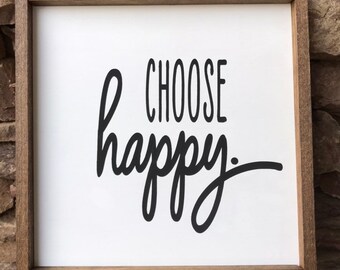May include: A white wooden sign with a brown frame, featuring the text "CHOOSE happy" in black cursive lettering.