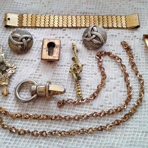 May include: A collection of gold-toned jewelry pieces, including a watch band, a chain, a keyhole charm, a clasp, and two Celtic knot charms.
