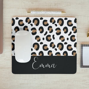 May include: A white mouse mat with a brown and black leopard print design. The bottom of the mouse mat is black with the name "Emma" written in white cursive.