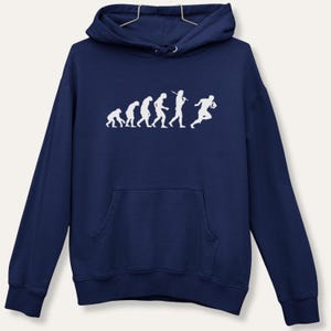 May include: Navy blue hooded sweatshirt featuring a white graphic illustrating the evolution of football. The design progresses from ape-like forms to a football player. The hoodie includes a front pocket and a drawstring hood.