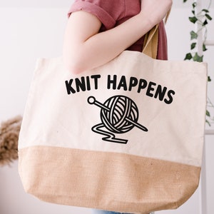 May include: A white canvas tote bag with brown burlap trim. The bag features a black graphic of a ball of yarn with a knitting needle and the text "Knit Happens".