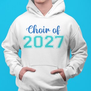 Könnte beinhalten: Ein weißer Kapuzenpullover mit einer Kängurutasche auf der Vorderseite. Auf der Brust befindet sich der Schriftzug "Choir of" in blauer Schreibschrift, darüber stehen die großen, blockartigen Zahlen "2027" in hellem Türkis mit weißem Rand.