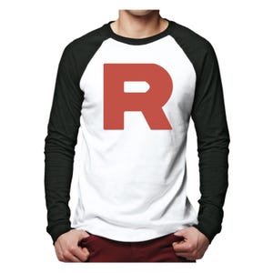 Może przedstawiać: Biało-czarna koszulka raglan z długim rękawem z dużą czerwoną literą "R" z przodu. Koszulka ma czarne rękawy i biały korpus. Czerwona litera jest wyśrodkowana.