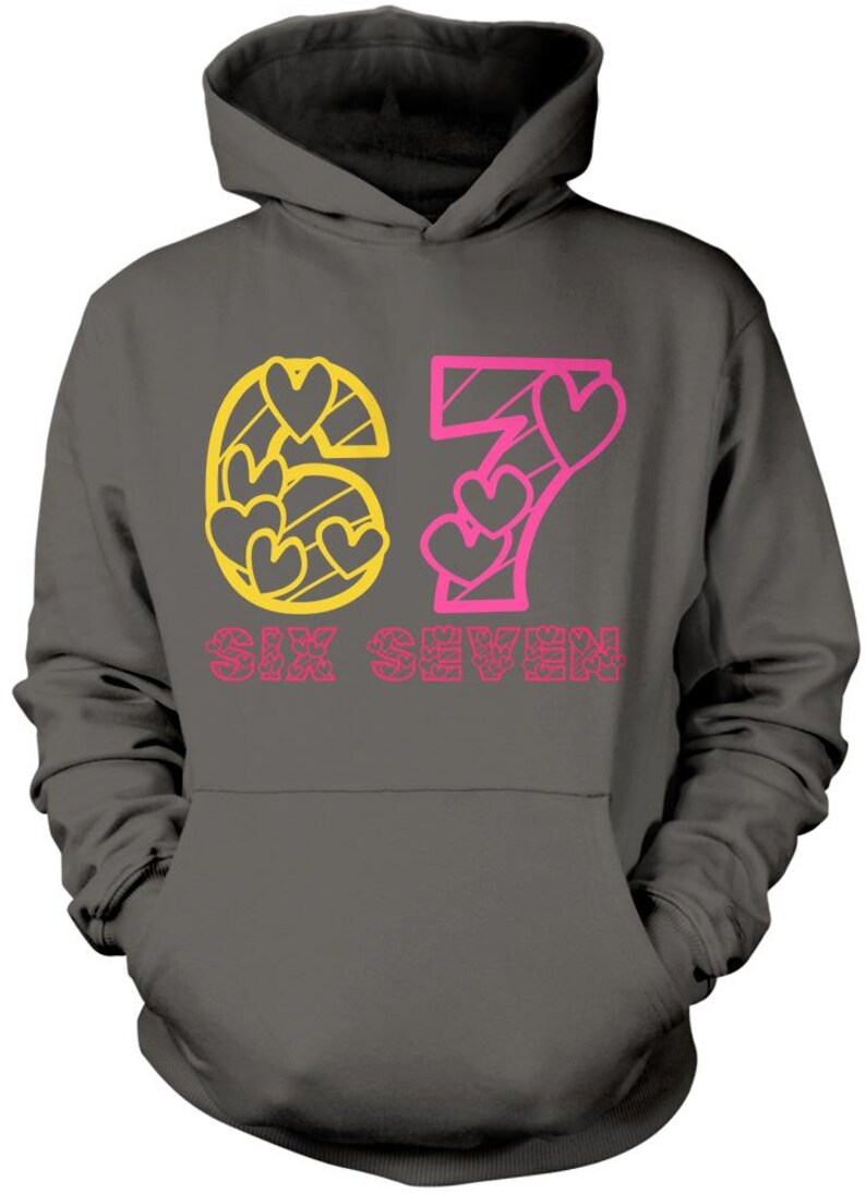 May include: Dark gray hoodie with a hood and a front pocket. The front features the number "67" in yellow and pink, with heart-shaped cutouts. Below the numbers, the words "SIX SEVEN" are printed in pink.