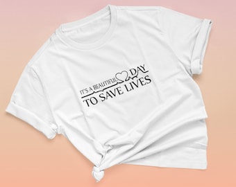 May include: White t-shirt with black text that reads "It's a beautiful day to save lives" with a heart and EKG line graphic.