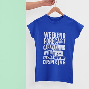 May include: A royal blue t-shirt with a white graphic that reads "Weekend Forecast: Caravanning with a chance of drinking". The graphic also includes a small illustration of a camper van and a beer bottle.